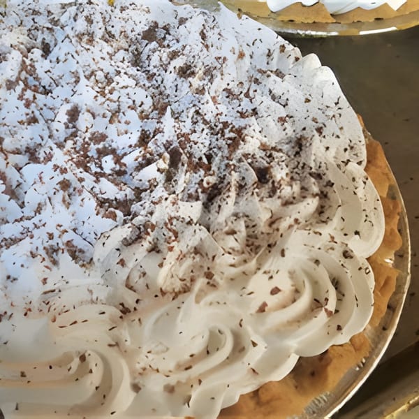 Close-up of a pie with fluffy white whipped topping and chocolate shavings from San Luis Rey Bakery.