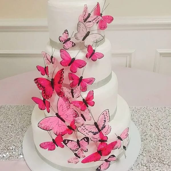 A multi-tiered white cake adorned with numerous pink and fuchsia butterfly decorations.