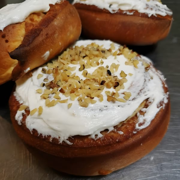 Three Mexican sweet breads with white frosting and chopped nuts on a metal surface.